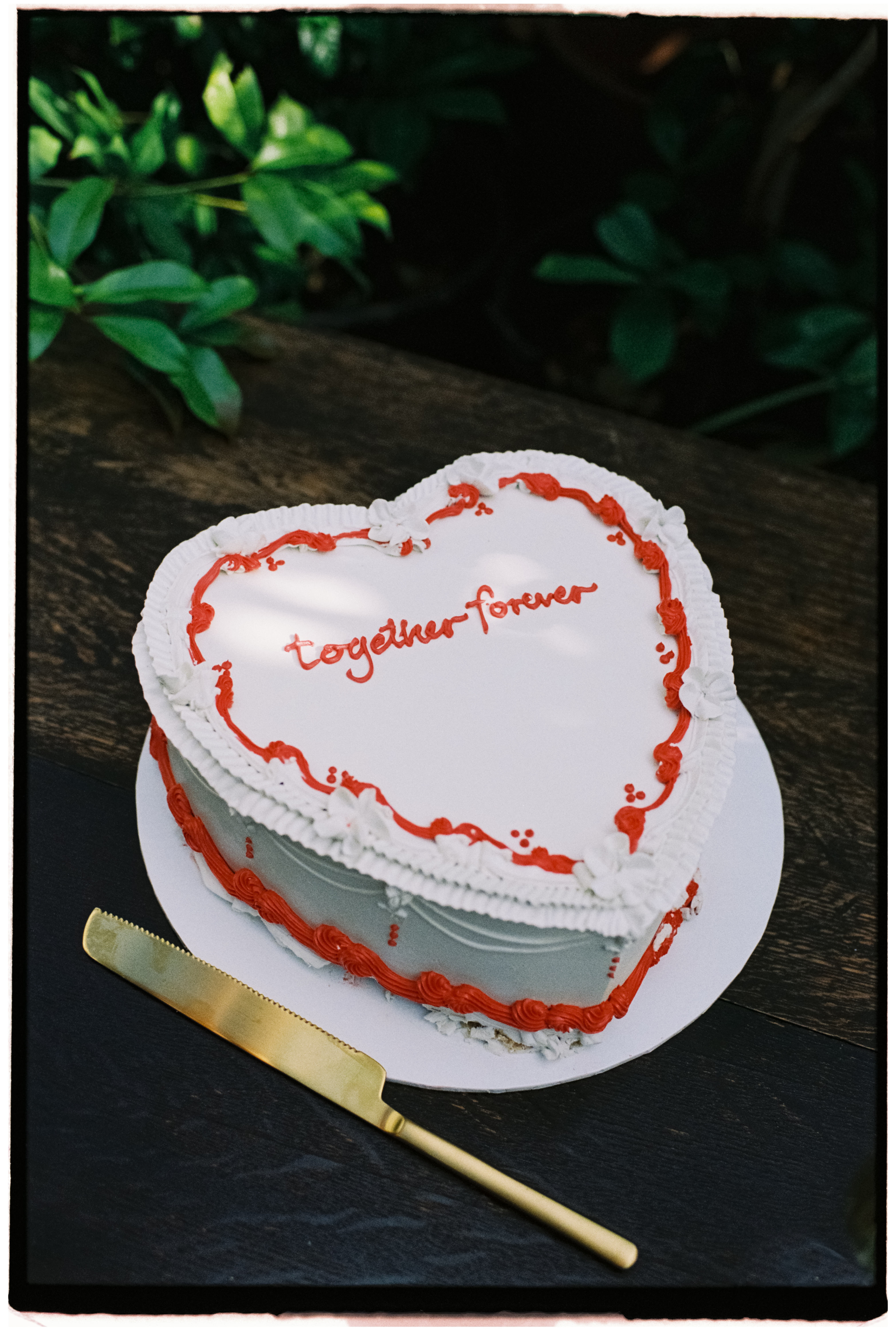 A white wedding cake with red frosting and the words Together Forever sits waiting to be cut at Glasshaus Outside in Richmond Melbourne.