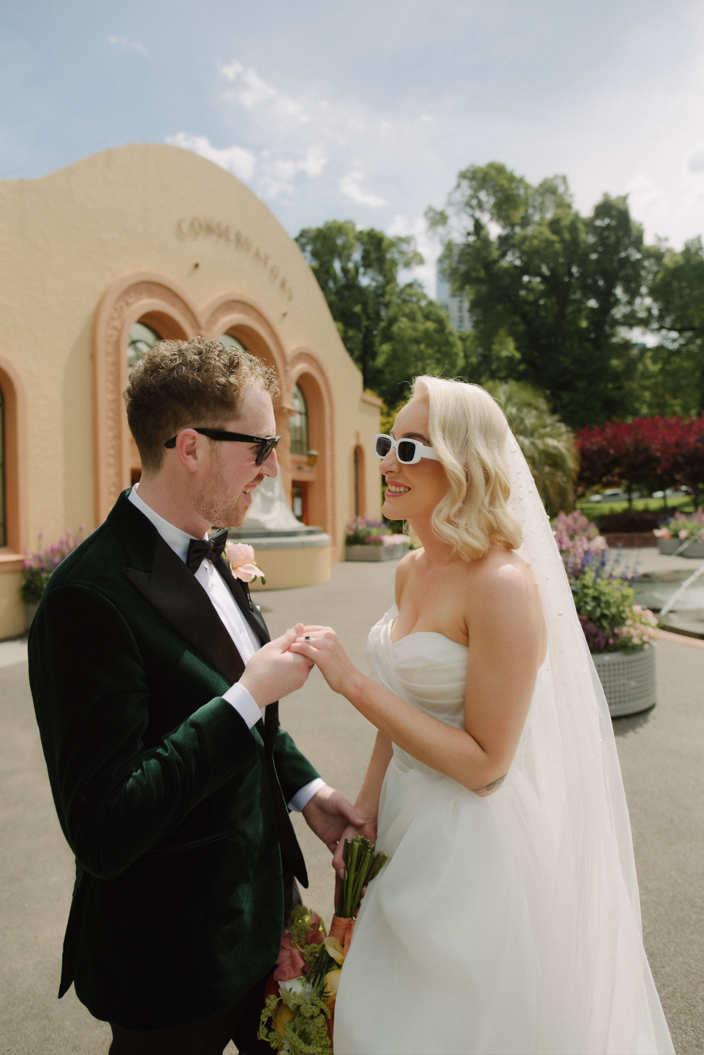 A bride and groom wearing sunglasses in Fitzroy Gardens during their photo portrait session.