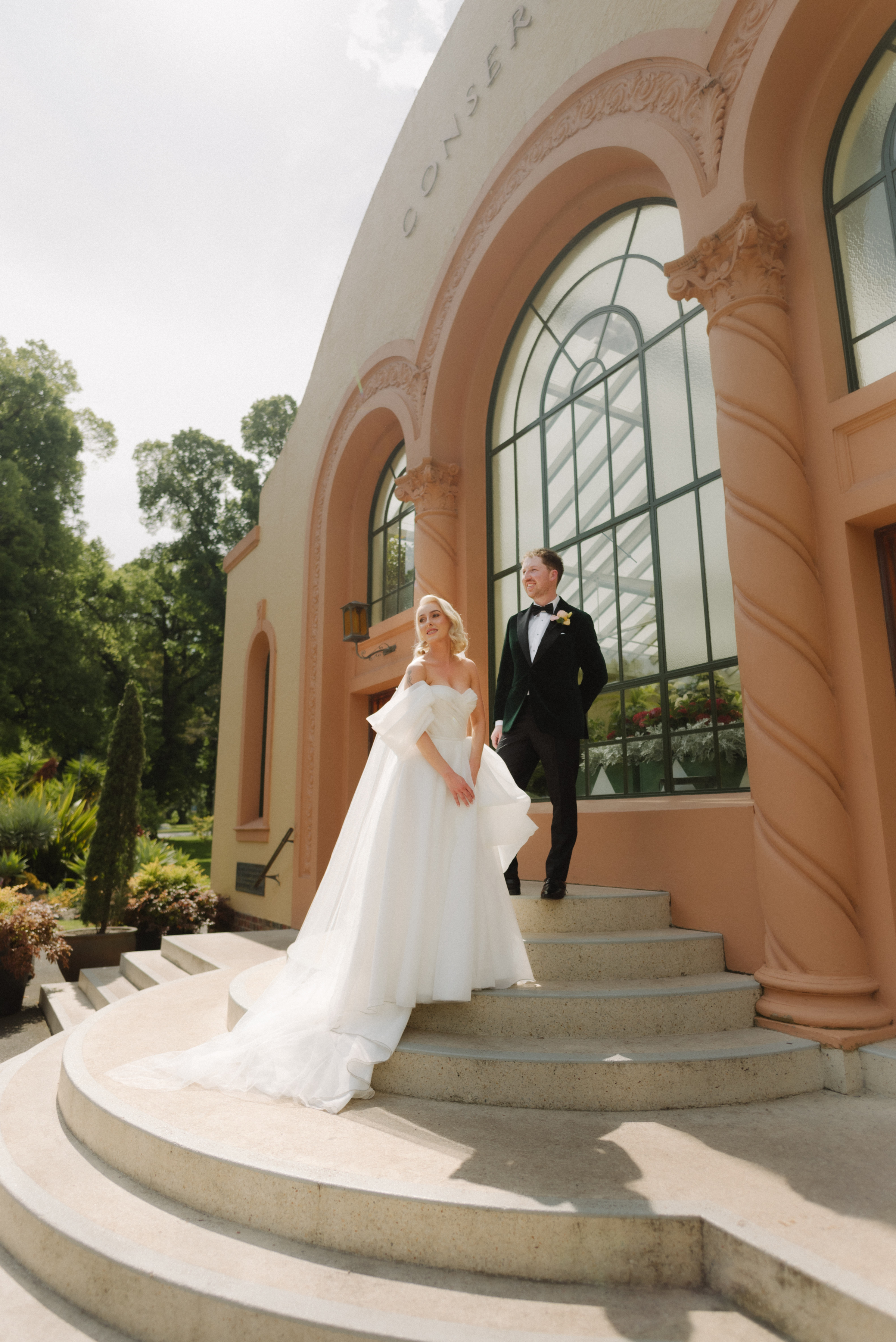 A bride and groom posing on the steps of the Conservatory at Fitzroy Gardens during their photo portrait session.