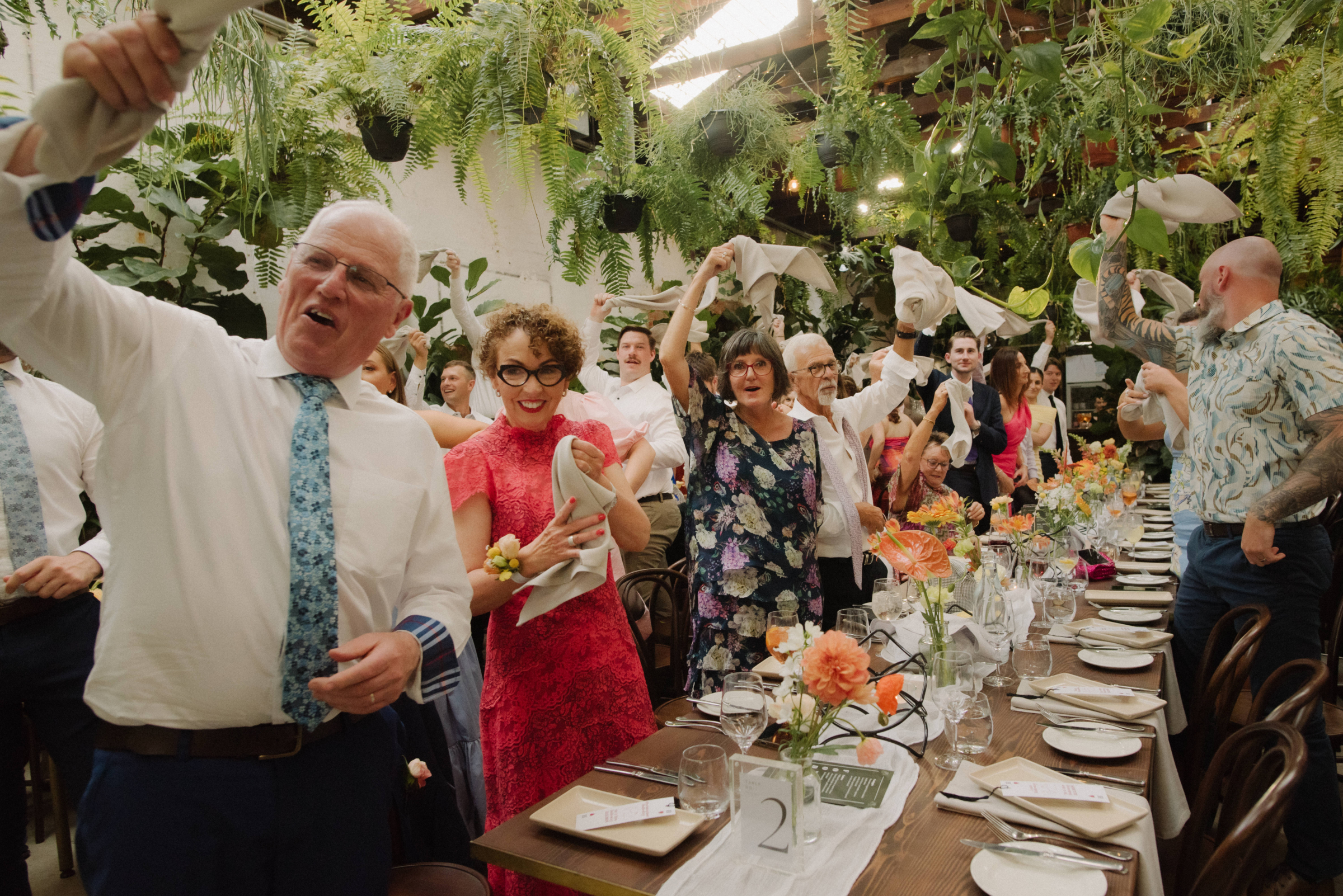 Wedding guests wave their napkins in the air as the bride and groom are about to enter their wedding reception.