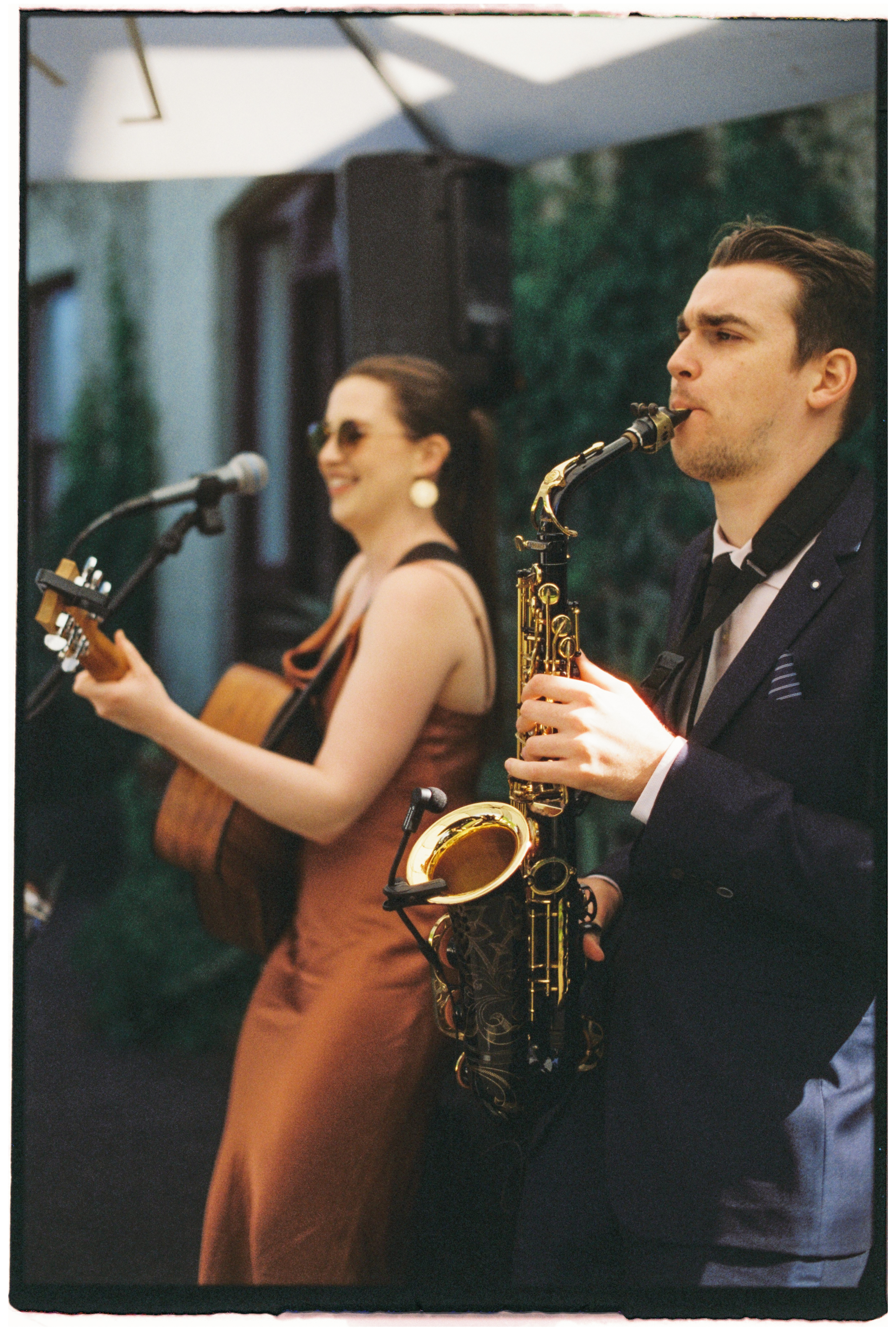 A 35mm film photo of a saxophonist and guitarist performing at a wedding at Gardens House, Melbourne.