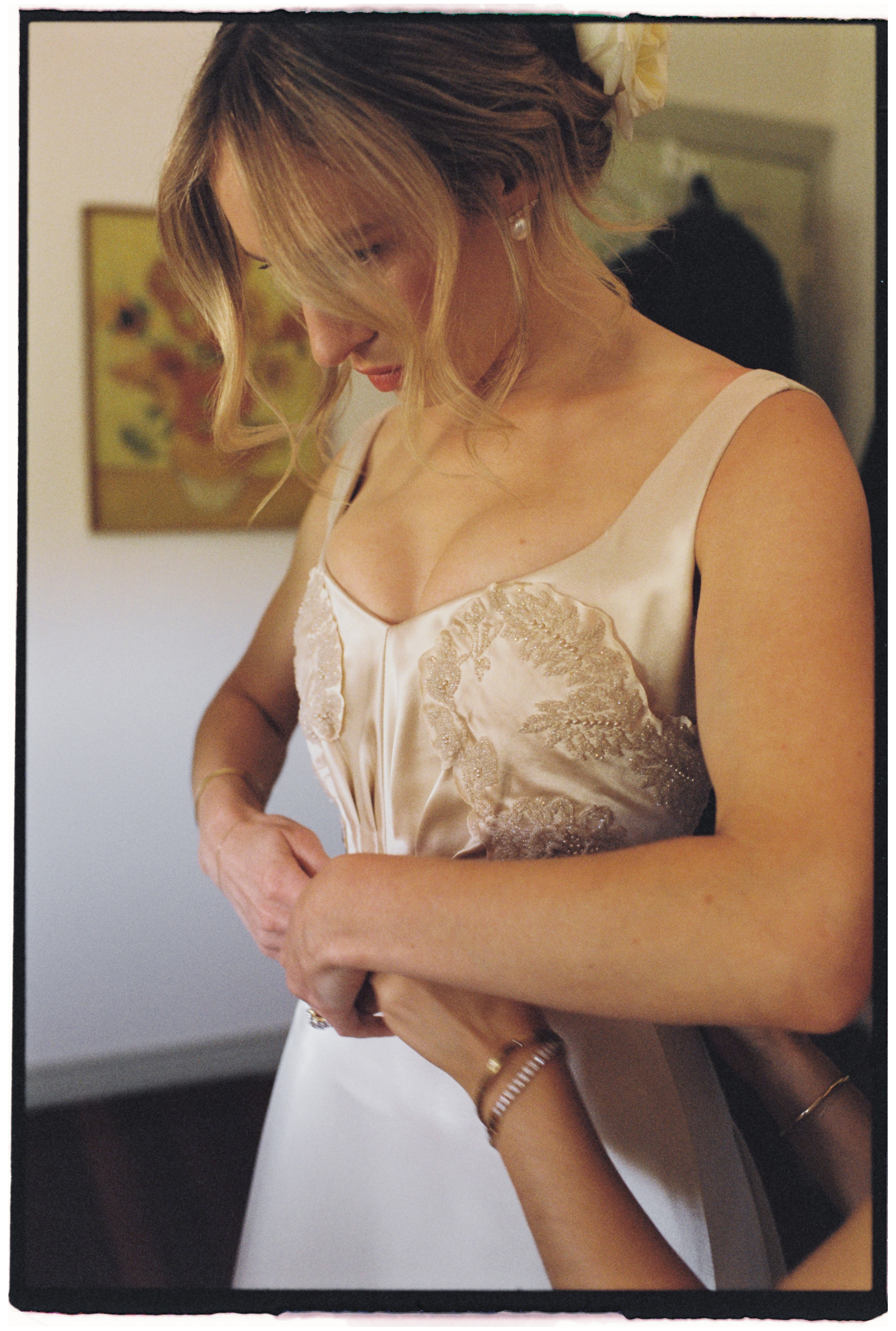 A 35mm film photo of the final adjustments being made to the bride's dress.