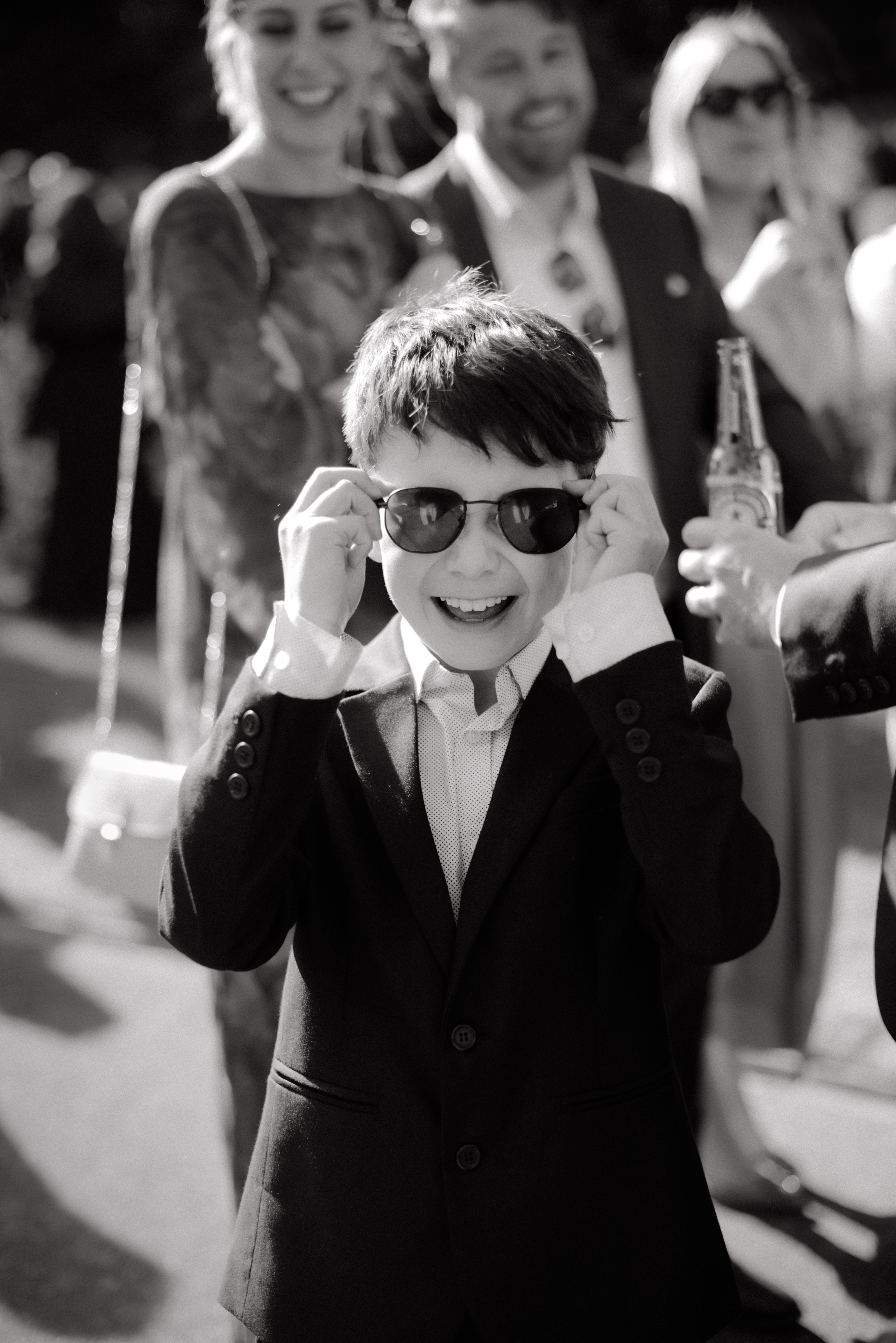 A black and white photo of a boy smiling wearing sunglasses.