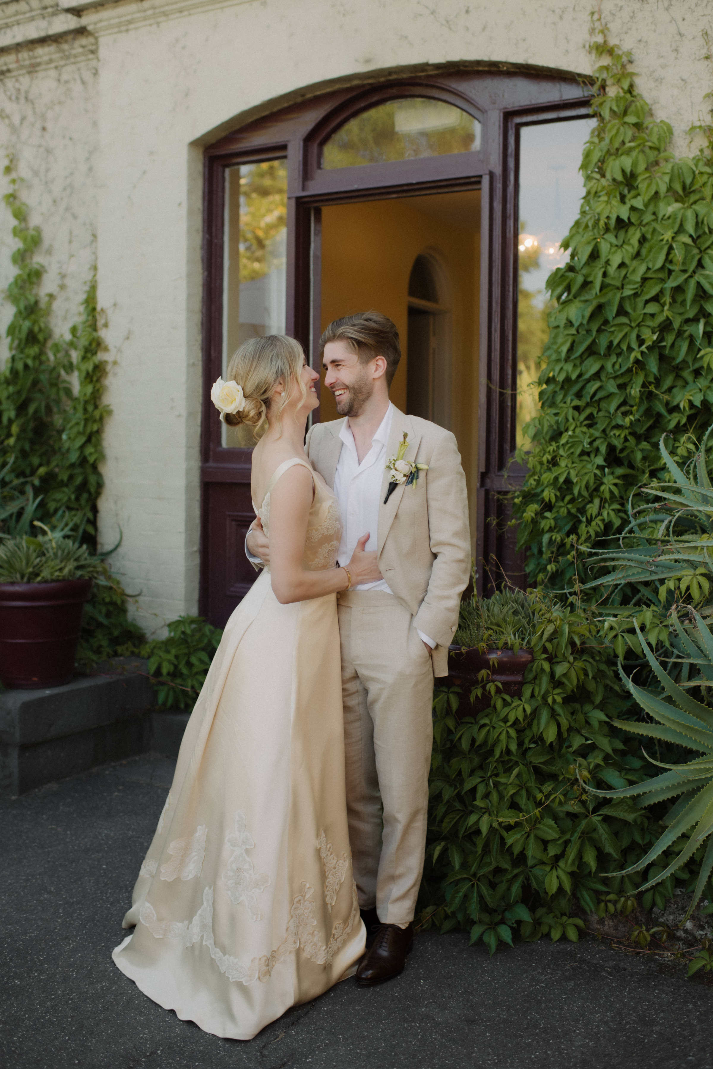 A bride and groom smiling at each other outside Gardens House, Melbourne.