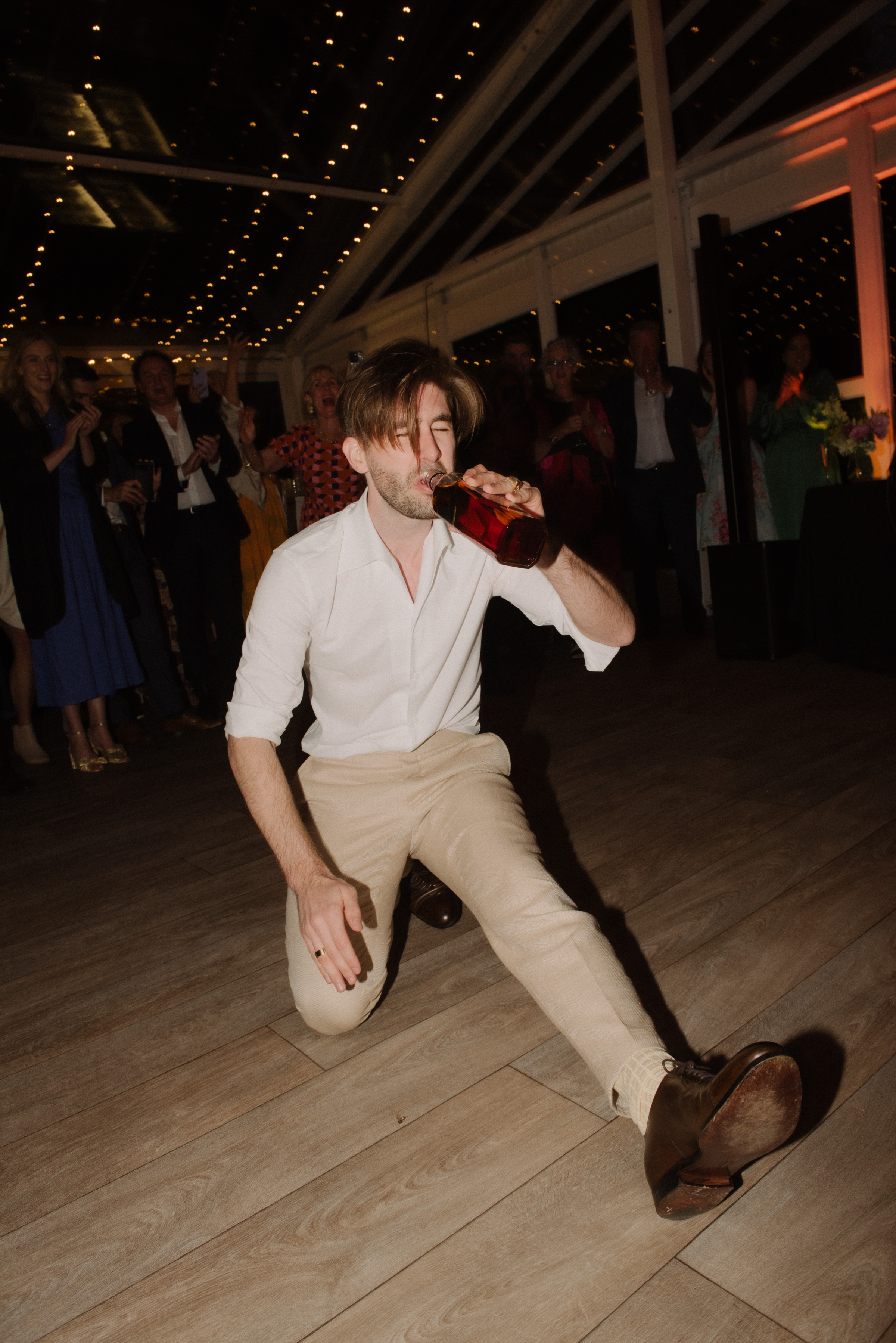 A groom swigs from a whisky bottle during a Greek wedding tradition at Gardens House, Melbourne.