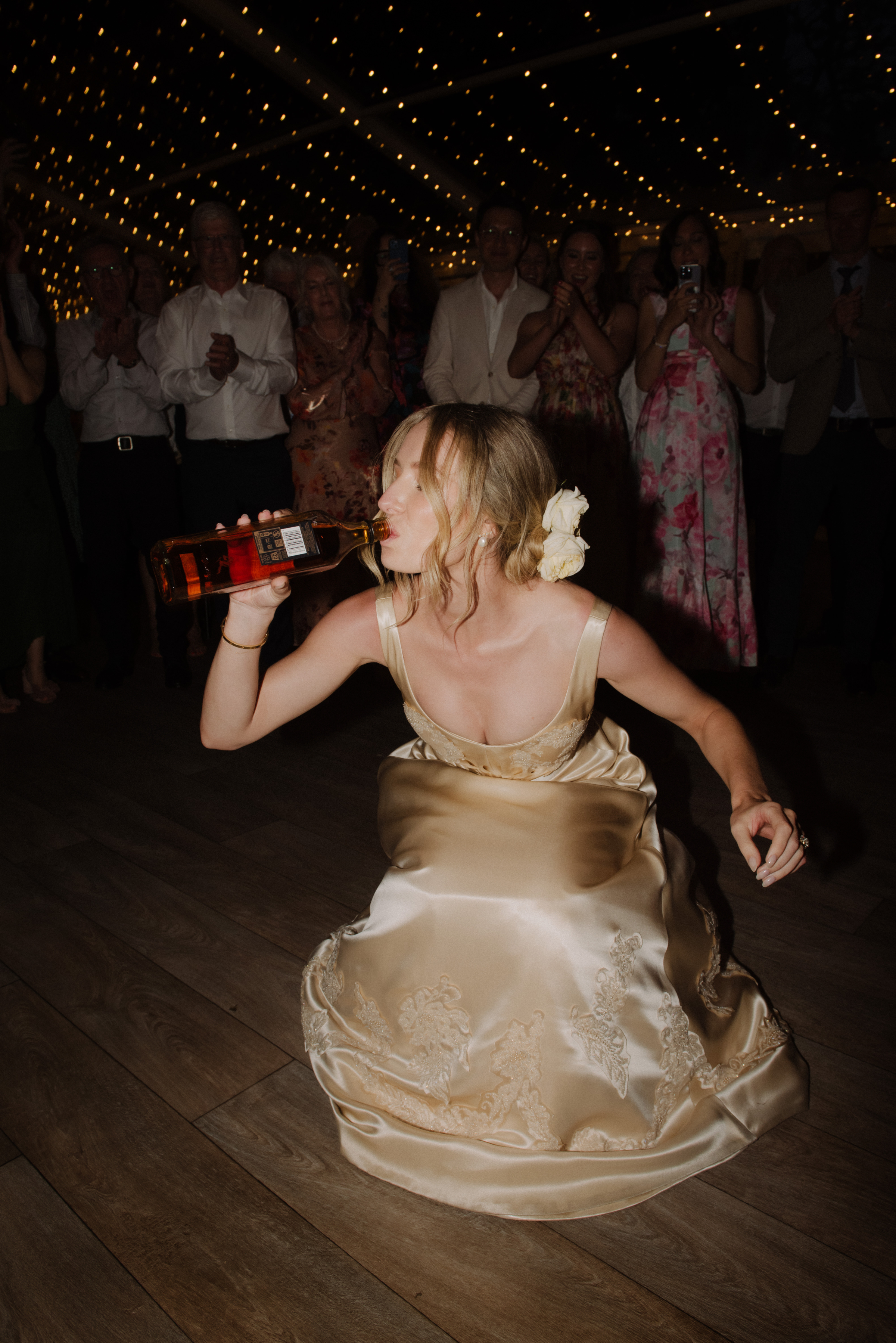 A bride swigs from a bottle of whisky during a dance tradition at Gardens House, Melbourne.